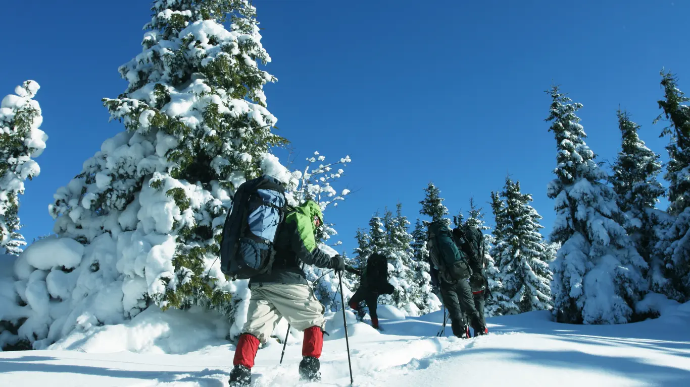 man trekking up a snowy mountain in deep snow
