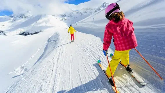 young child skiing down a well used slope