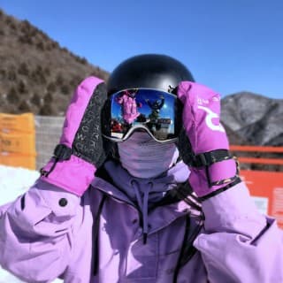 Lydia wearing mauve ski wear and mitts. Her face is covered in a mauve scarf and reflective eye protectors